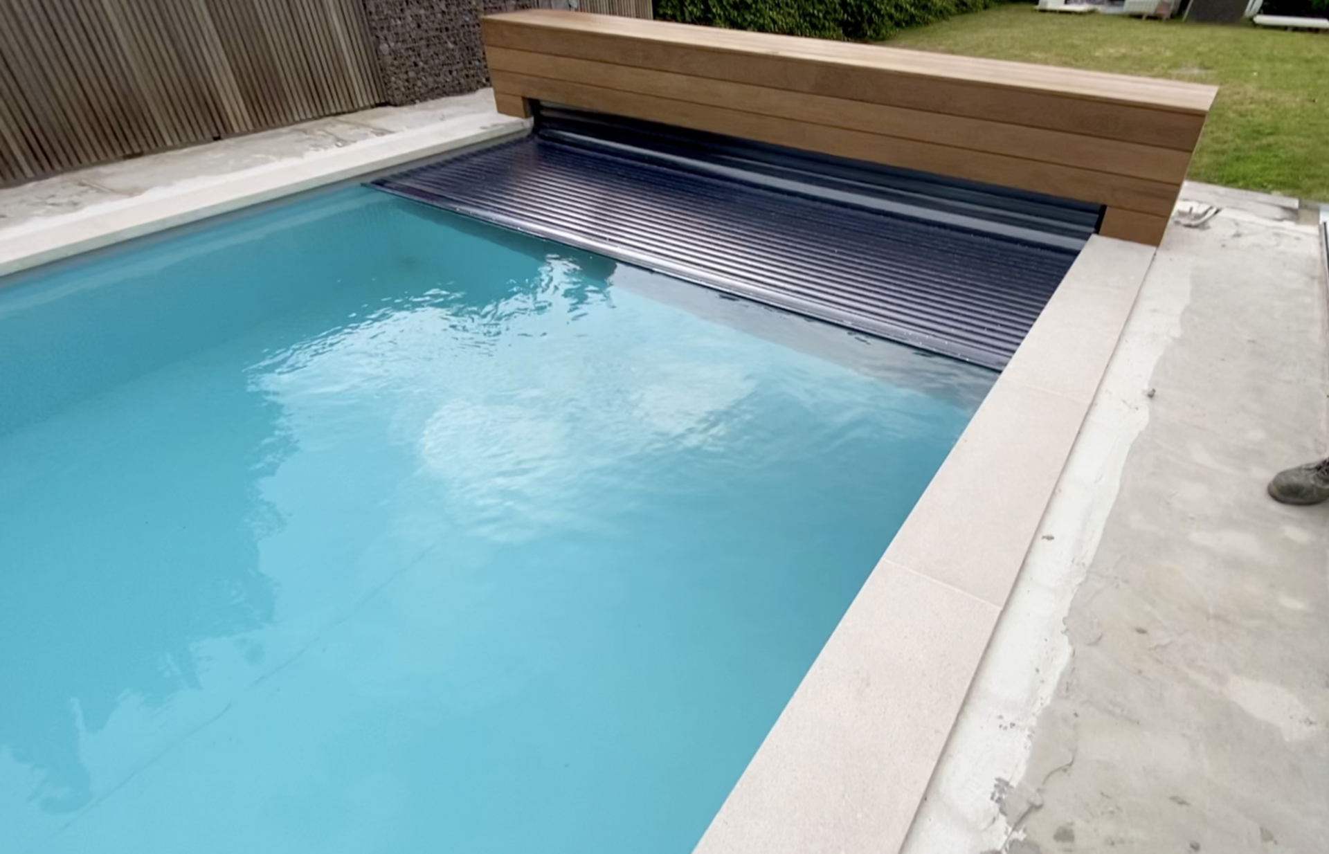 Rechthoekig zwembad met turkoois water en lichte natuurstenen boord — realisatie Liner Plaatsen